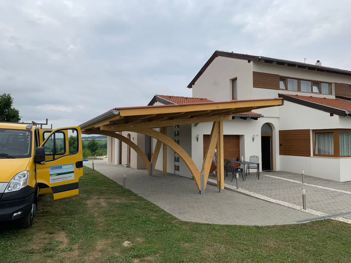 Großer Holz-Carport mit Bogenstützen vor Wohnhaus