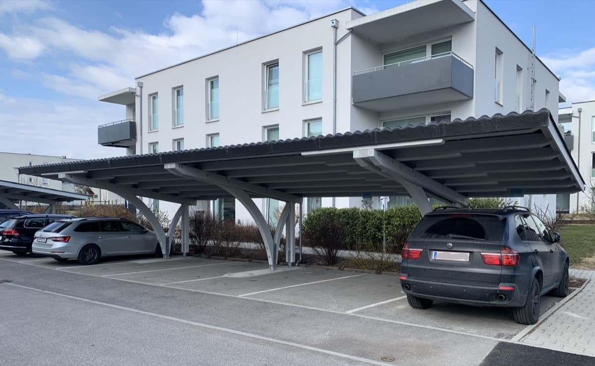 Reihen-Carport mit Stahlbögen vor Wohnanlage