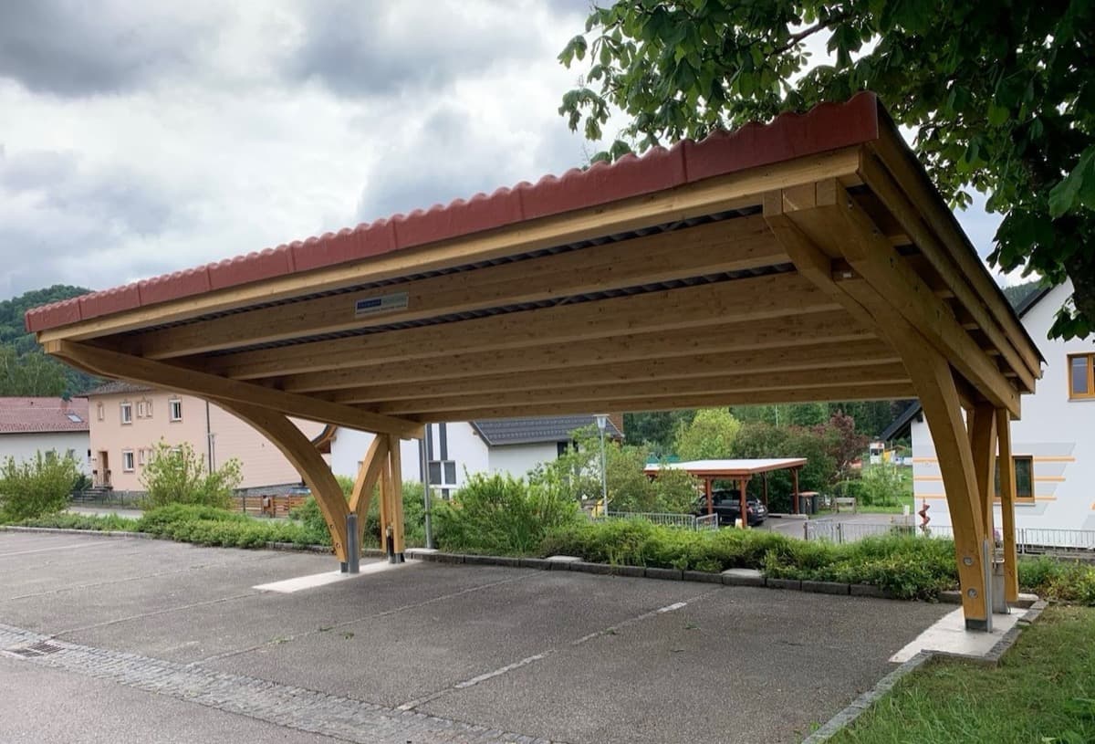 Freistehender Doppelcarport mit Bogenstützen und rotem Blechdach