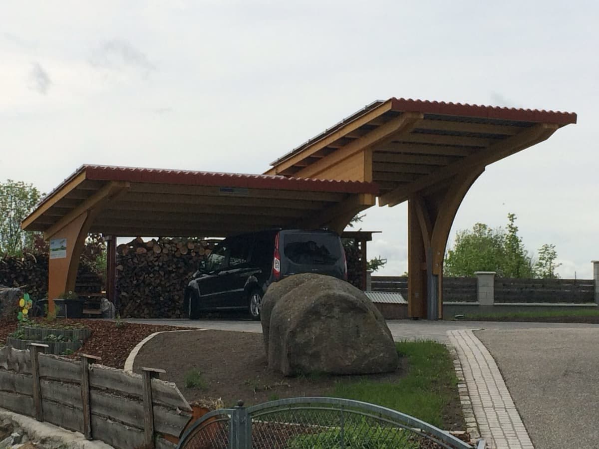 Doppelcarport mit geschwungenen Holzbogen und Brennholzlager