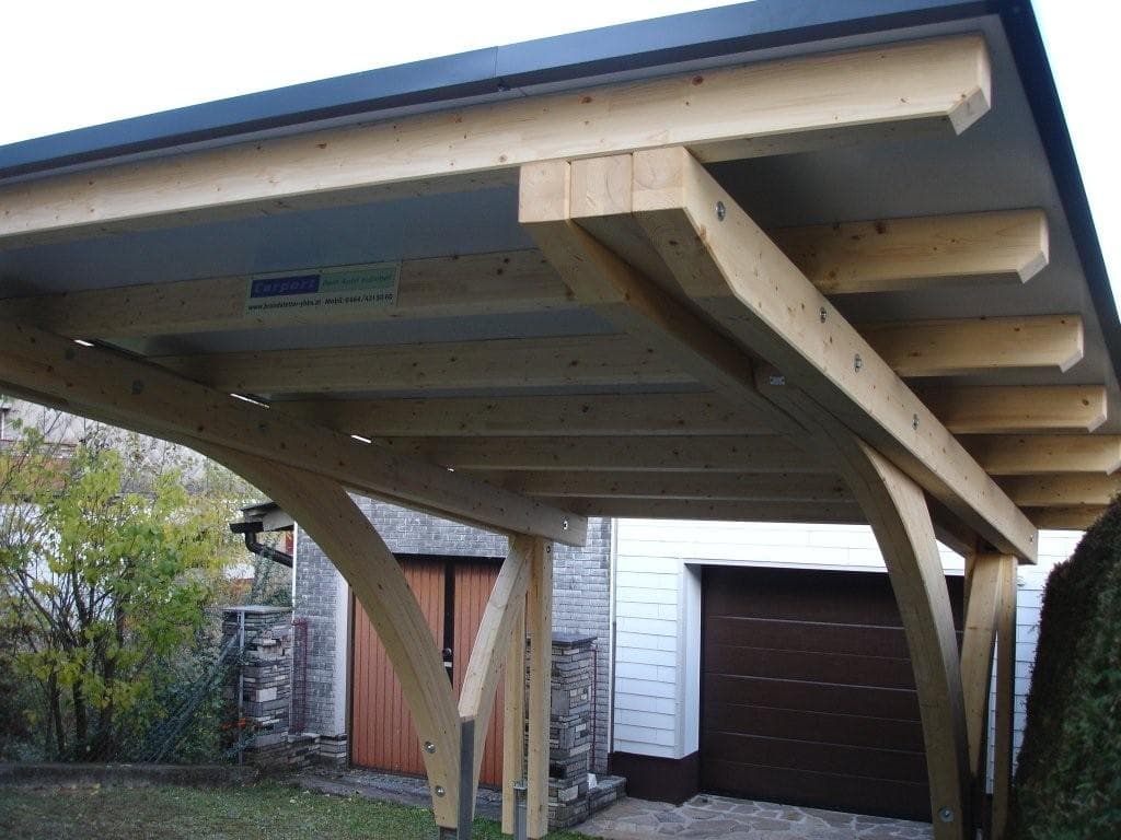 Einzelcarport aus Leimholz mit Bogenstützen vor Garage im Rohbau