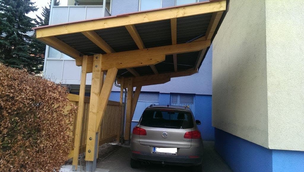 Holz-Carport an Hauswand mit geparktem Auto