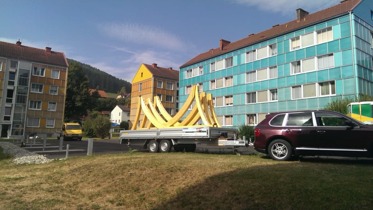 Anhänger mit Bogenbinder-Elementen vor Wohngebäude